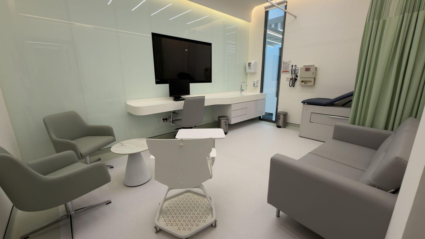 Consultation room with lounge seating, a large screen and an examination bed