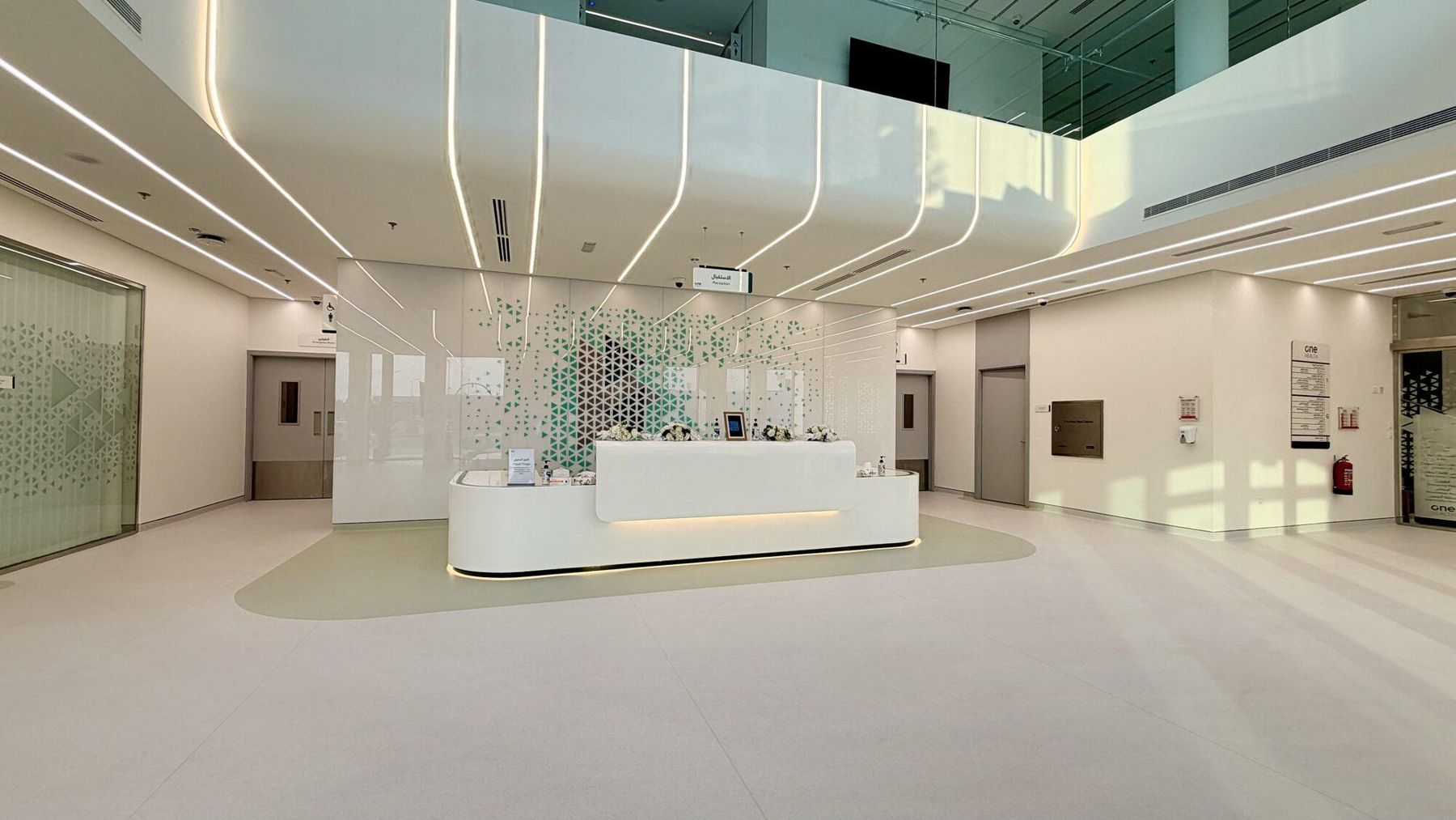 Bright double-height reception atrium with a curved white front desk